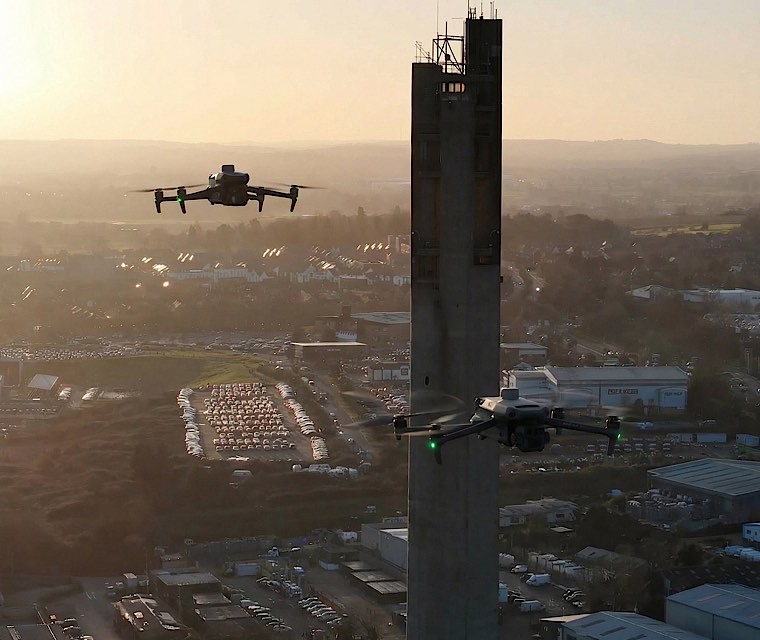 Two drones flying at golden sunset over industrial area for special event coverage