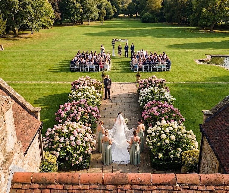 Aerial drone view of outdoor wedding ceremony, bride walking through garden