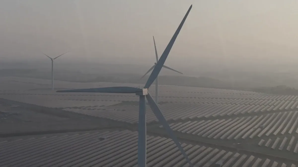 Aerial view of wind turbines above a solar farm at dawn