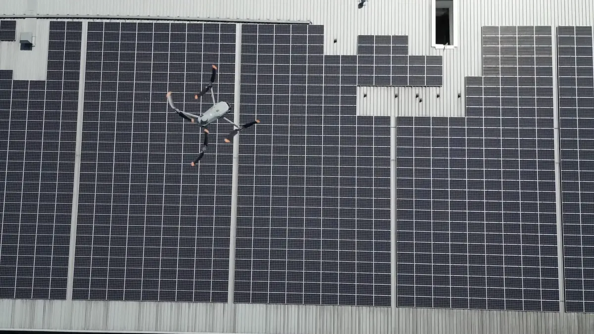 Drone inspecting a large commercial rooftop solar panel array