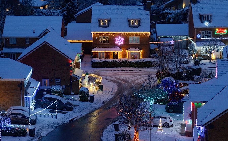 Aerial view of residential street covered in snow with Christmas lights