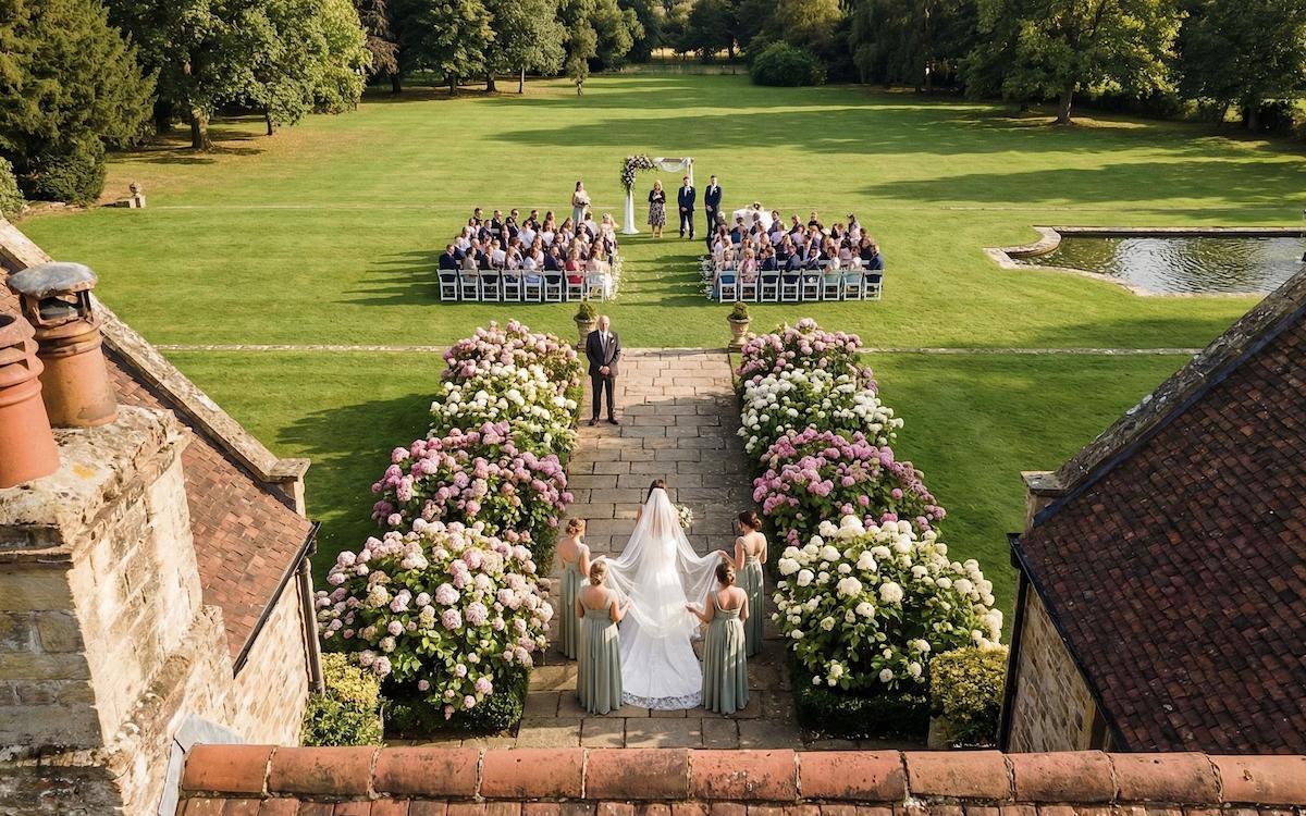 Bride walking the flower-lined aisle captured from above — drone aerial shot at a Northamptonshire wedding